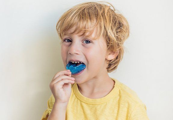 Young boy placing a blue mouthguard