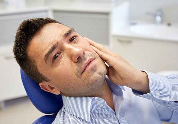 Man in need of tooth replacement holding jaw