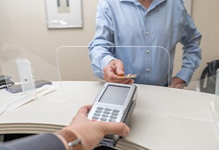 A man using his credit card to pay the cost of dental care